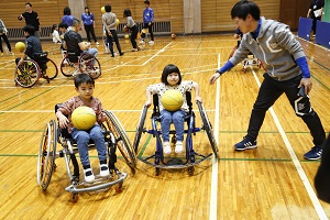 写真：車いすの操作とドリブルを同時にする体験で苦戦する子どもたち