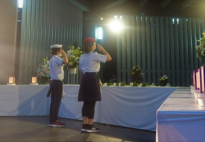 写真：戦没者追悼式（戦没者の慰霊碑に敬礼する小学生2人）