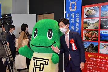 写真：区民ホールで開催された福井フェアで恐竜の着ぐるみと一緒に記念撮影する樋口区長