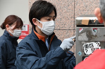 写真：樋口区長が秋葉原駅前のステッカーをはがしている様子