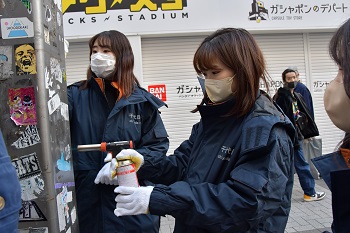 写真：職員が秋葉原駅前のステッカーをはがしている様子